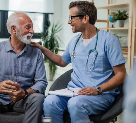 Happy doctor talking to senior male patient while being in a home visit.